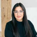 Woman smiling at camera while wearing a black sweater. She is also wearing glasses. Garathi Khanna C.